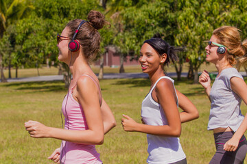 Tres jovenes mujeres haciendo deporte, corriendo al sol un día de verano.