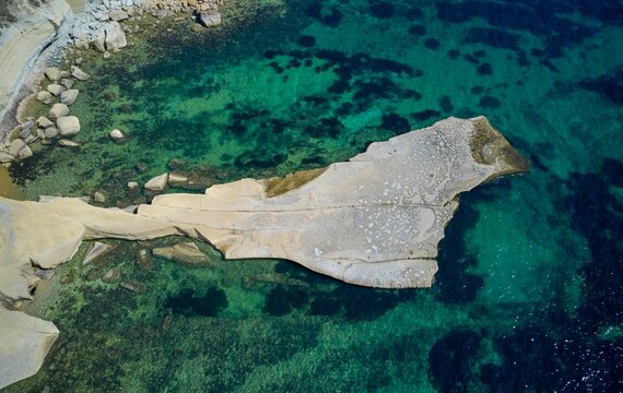 Aerial shot of the white chalk limestone cliffs of Munxar among the clear waters in Malta