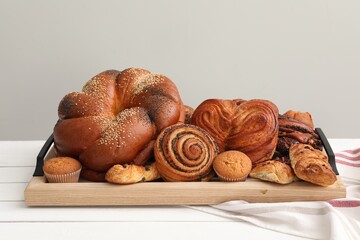 Different tasty freshly baked pastries on white wooden table