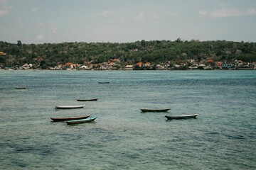 Fishing boats in Nusa Lembongan, Bali with seaweed farms and houses in the background