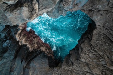 Aerial top view of a heart-shaped cave against sea waves