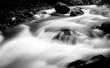 Long-exposure monochrome shot of the waterfall flowing over the rocks and stones