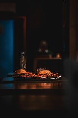 Vertical shot of burgers, french chips and lemonade on the table in the dark room