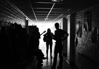 Grayscale of the silhouettes of band members practicing in the school hallway