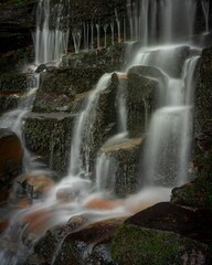 Fototapeta na wymiar Vertical long exposure shot of a waterfall surrounded by rocks, Blue Mountains, Australia