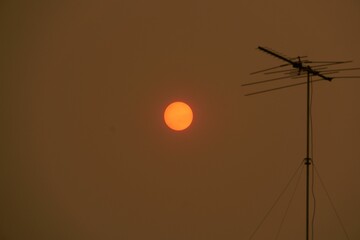 Antenna silhouette and red sun on the clear sky
