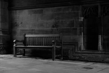 Fototapeta na wymiar Grayscale shot of an empty bench near the entrance of a building.