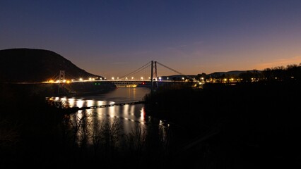 Bear Mountain bridge lit up at night over the river