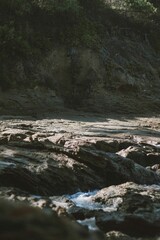 Vertical shot of rocky ground with a mountain near a stream