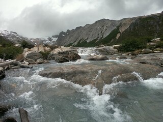 River flowing between rocks and steep mountains on a foggy day
