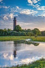 Fototapeta na wymiar Vertical shot of a lighthouse in Behrensdorf reflected on waters during sunset near Baltic sea