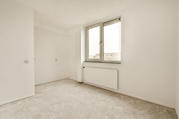 an empty room with white walls and no one person standing in the corner looking out at the view from the window