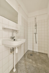 a bathroom with a sink, mirror and shower head mounted on the wall next to it is an empty white tiled floor