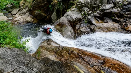 Fotobehang High angle shot of people canyoning through a stream on the side of a mountain in France © Arne SchrÖter/Wirestock Creators