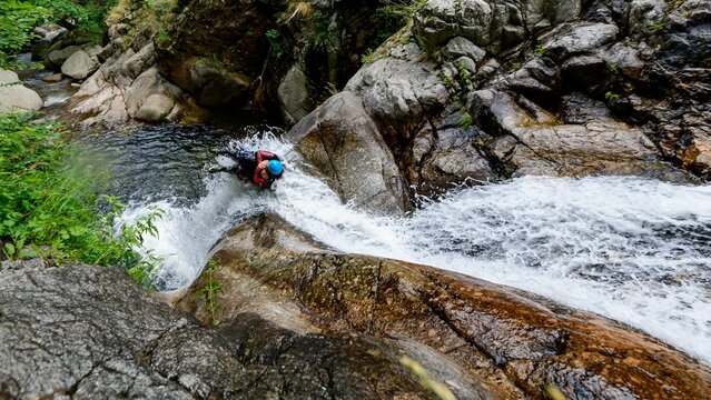 High angle shot of people canyoning through a stream on the side of a mountain in France
