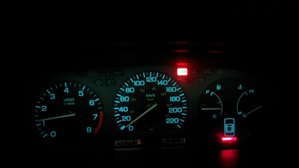 Closeup view of red and blue car speedometers and indicators in the dark of night