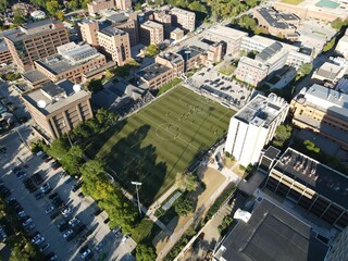 Drone shot over soccer field between buildings on sunny day