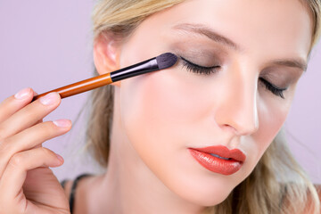 Closeup beautiful girl with flawless applying alluring eye shadow makeup with eyeliner brush....