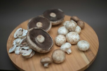 Closeup of raw Agaricus bisporus mushrooms on the wooden round board