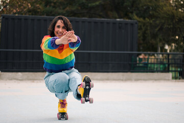 bella mujer latina sonriendo, con frenillos, maquillaje y en patines con polera de arcoíris lgbtq en la calle practicando patinaje