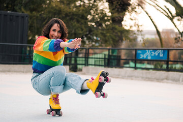 bella mujer latina sonriendo, con frenillos, maquillaje y en patines con polera de arcoíris lgbtq en la calle practicando patinaje