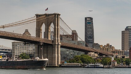 Huge cargo ship crossing under the Brooklyn Bridge on a sunny day. New York, USA