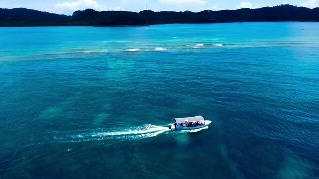 Aerial view of tourists riding a motor boat in mesmerizing turquoise sea on a warm day