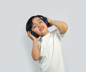 child wearing headphones listening to music, body in front, head inclined, arms up holding headphones, straight black hair, latin boy Mexican, light skin, pink cheeks, White shirt, White background, 
