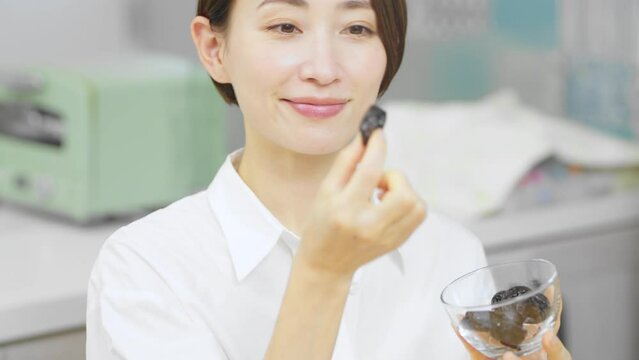 プルーンを食べる若い女性　飲食イメージ	
