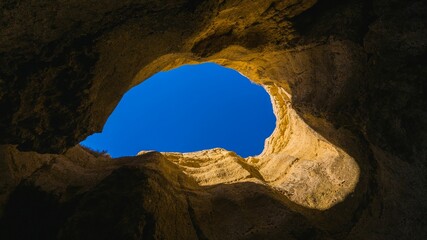 Low-angle view of an opening between the rocks with the blue sky visible from it