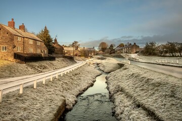 Flowing river surrounded by houses and snow