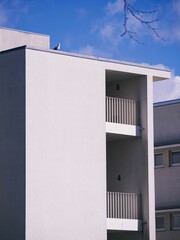 White building with balconies and a single person walking by
