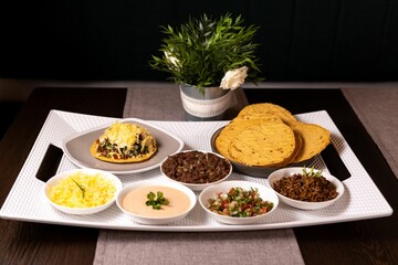 a tray holds various dishes of food and bowls of dip sauces