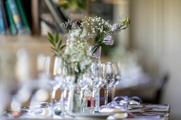 Closeup of a festive table with white dishes and glasses, blurred background