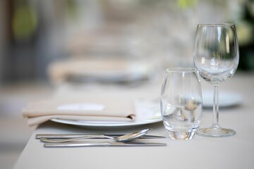 Closeup of a festive table with white dishes and glasses, blurred background, just married