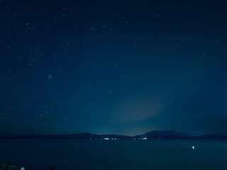 night sky with stars above ocean and mountains near shore - pf0738
