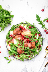 Healthy useful salad with grilled chicken liver, green apple, pomegranate seeds and fresh arugula. White kitchen table background, top view