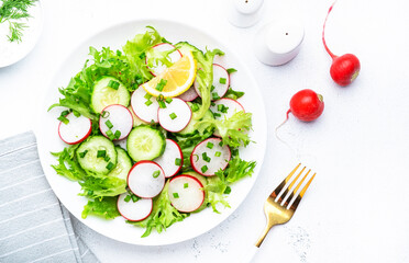 Healthy summer salad with fresh radishes, cucumbers, lettuce and green onion with greek yogurt dressing, white table background, top view