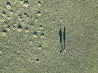 two people are standing alone among the grass on top of a hill