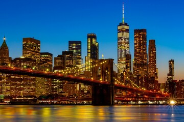Fototapeta premium Stunning night-time view of the iconic Brooklyn Bridge in New York City, illuminated by city lights