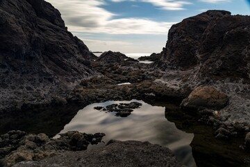 Scenic view of coastal rocks with the sea in the background under the cloudy blue sky