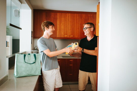 Father and son unpacking groceries in kitchen together