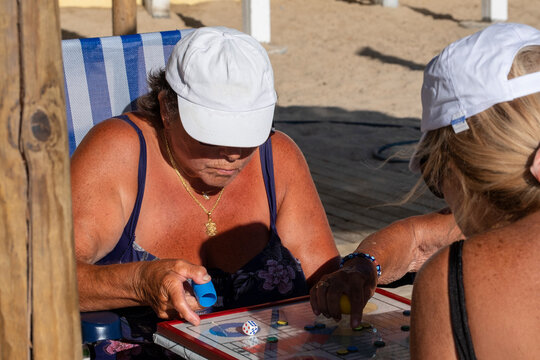 A group of older women playing a board game . - Powered by Adobe
