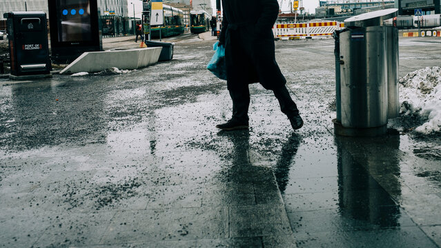 A man near a trash bin with a bag in his hand