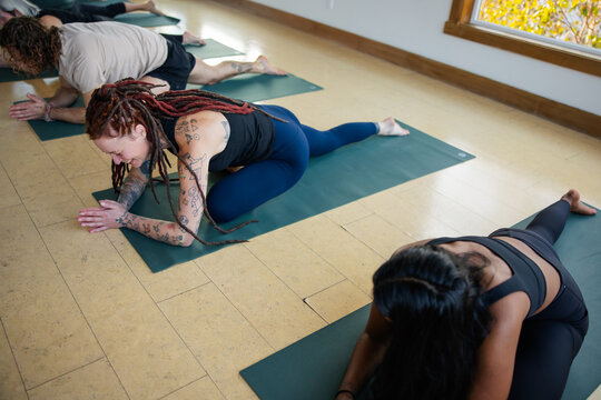 Woman smiling and enjoying group yoga class in pigeon pose.