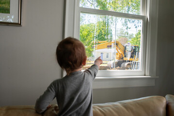 Child Pointing out the Window at an Excavator Outside his House