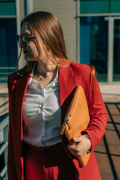 Woman in red suit with leather folder in hands