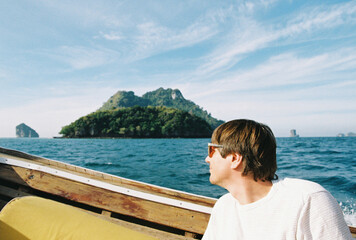 A man in a boat in tropical waters in Thailand.