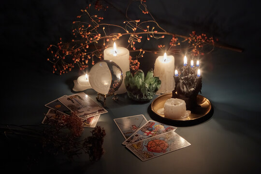 Tarot cards and magic sphere with burning candles in dark.