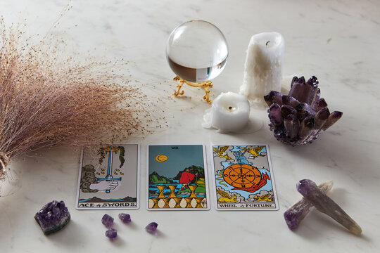 Tarot cards spread, candles, magic sphere and stones.